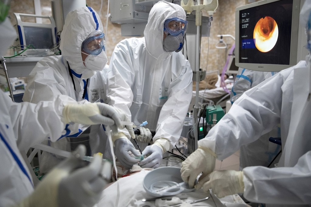 In this photo taken on Friday, May 15, 2020, Dr. Osman Osmanov, center, and Dr. Konstantin Glebov, center left, perform tracheal intubation on a coronavirus patient on artificial lung respiration at an intensive care unit of the Filatov City Clinical Hospital in Moscow, Russia. Moscow accounts for about half of all of Russia's coronavirus cases, a deluge that strains the city's hospitals and has forced Osmanov to to work every day for the past two months, sometimes for 24 hours in a row. (AP Photo/Pavel Golovkin)