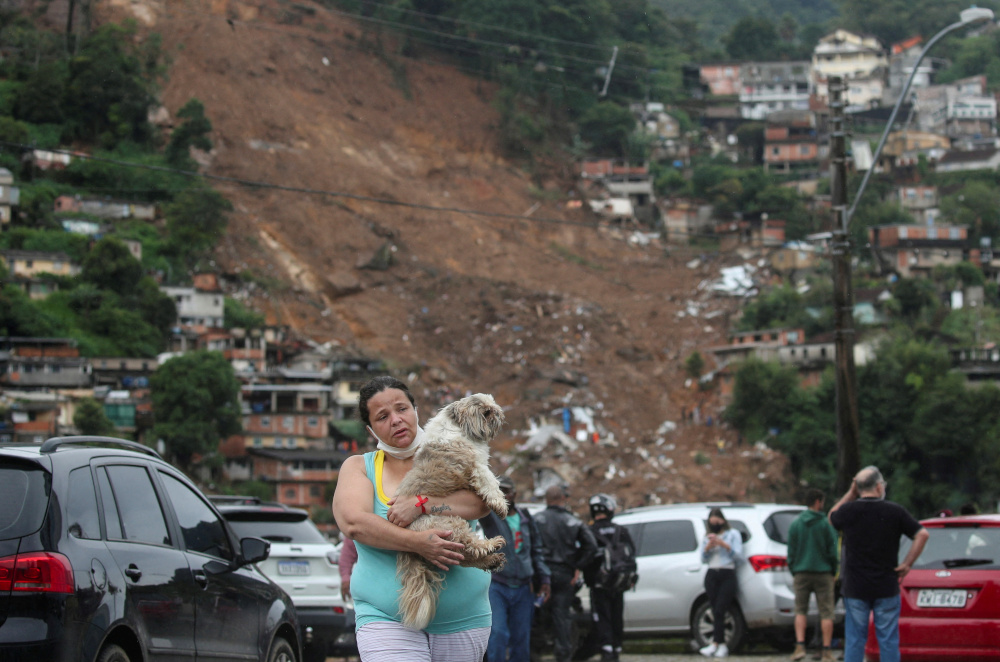 FILE PHOTO: Viviane de Souza, 42, carries her dog at a shelter for displaced people after a mudslide at Morro da Oficina, following heavy rainfall in Petropolis, Brazil February 18, 2022. REUTERS/Ricardo Moraes/File Photo