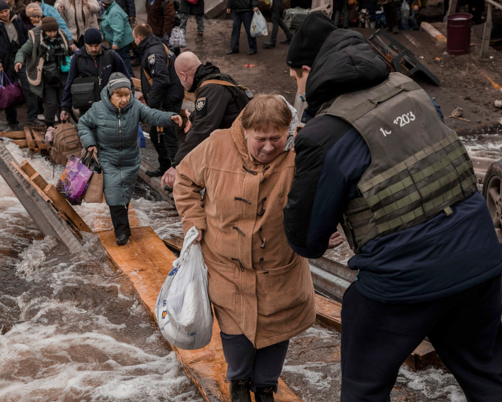 Local residents cross a destroyed bridge as they evacuate from their town in Irpin, near Kyiv, Ukraine March 7, 2022. Jedrzej Nowicki/Agencja Wyborcza.pl via REUTERS ATTENTION EDITORS - THIS IMAGE WAS PROVIDED BY A THIRD PARTY. POLAND OUT. NO COMMERCIAL OR EDITORIAL SALES IN POLAND.