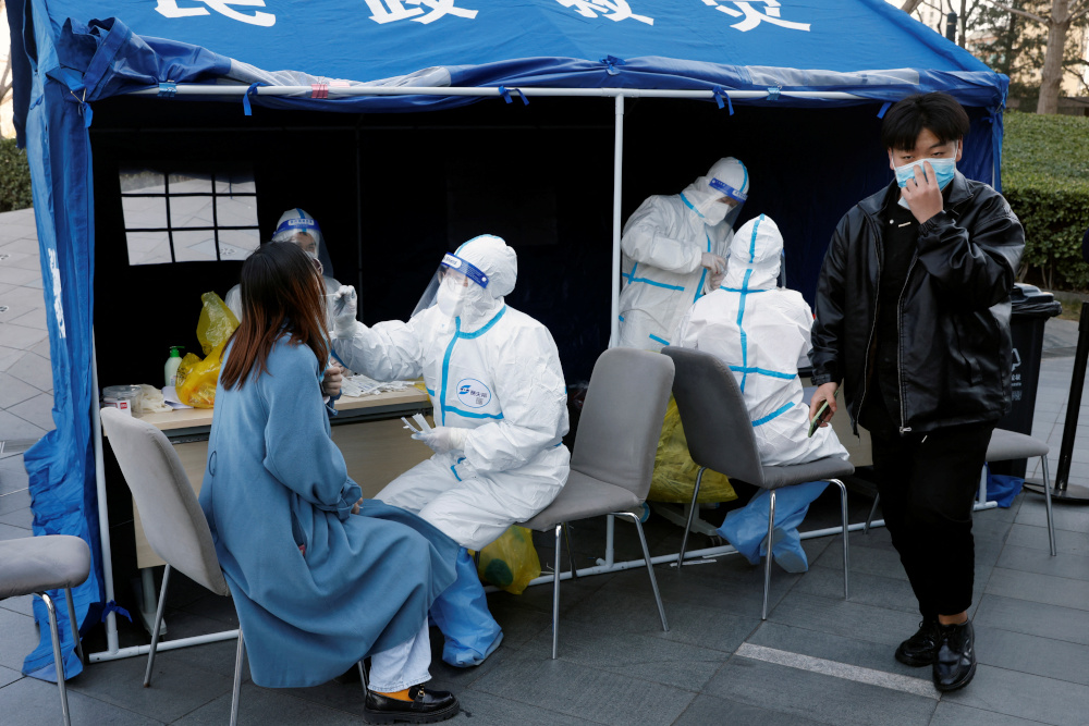A medical worker in a protective suit collects a swab from a resident during a mass testing for the coronavirus disease (COVID-19) at a makeshift nucleic acid testing site outside a shopping mall in Beijing, China March 21, 2022. REUTERS/Carlos Garcia Rawlins