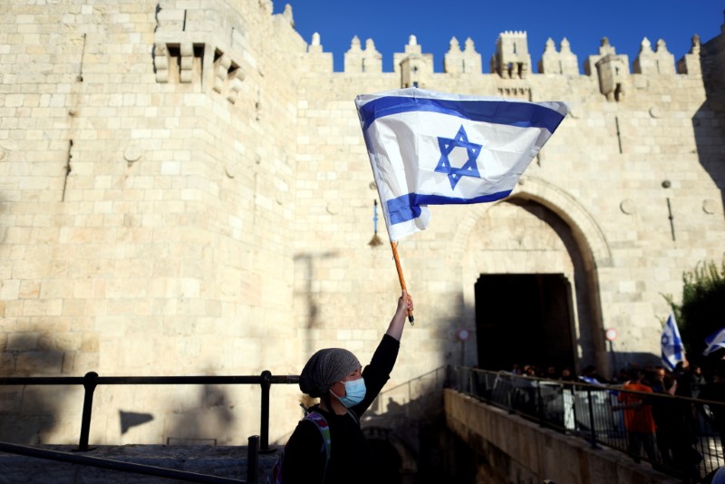 FILE PHOTO: An Israeli woman holds a flag by Damascus gate just outside Jerusalem's Old City June 15, 2021. REUTERS/Ronen Zvulun/File Photo