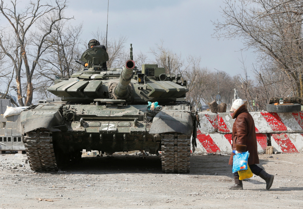 A local resident walks past a tank of pro-Russian troops during Ukraine-Russia conflict in the besieged southern port city of Mariupol, Ukraine March 18, 2022. REUTERS/Alexander Ermochenko