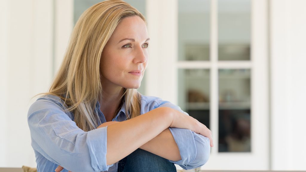 Woman sitting outside the house and thinking about her new idea. Pensive mid woman relaxing at home on a holiday. Portrait of mature woman planning her future.
