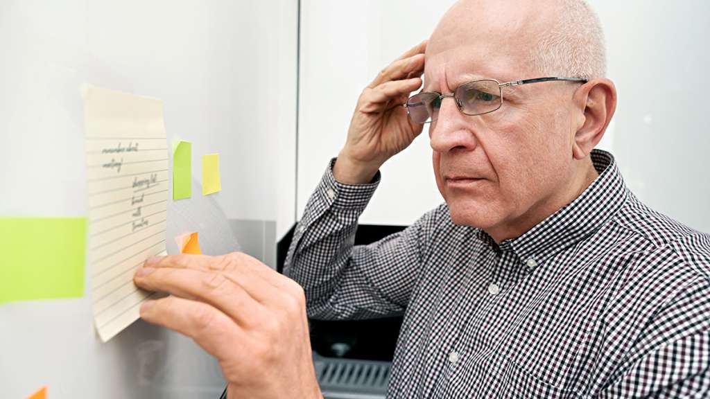 Elderly man looking at notes. Forgetful senior with dementia, memory problem, health concept