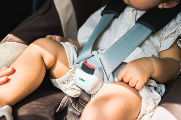 Close up fastening safety belt to baby in car seat. Toddler girl with security belt in vehicle. Safety car. Family travel concept