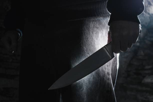 Dark photo of a man holding a big knife, crime concept.